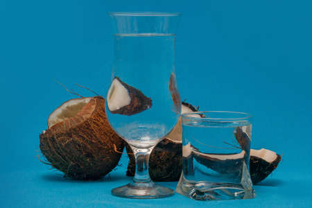 Coconut halves distorted through glasses with waterの写真素材