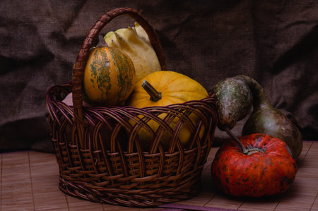 Autumn still life with pumpkins in a basket on a dark backgroundの写真素材