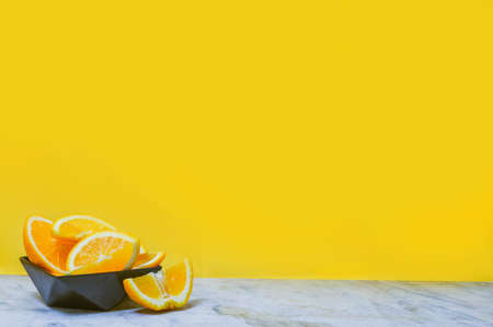 Sliced oranges in a black late on yellow backgroundの写真素材