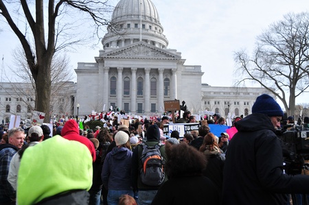 Madison, Wisconsin, USA â 2-15-11 â Large crowd of protesters, wielding signs on grounds of the Wisconsin state capital, who are there to protest the bill to balance the state budget by restricting collective bargaining rights for state union employeeのeditorial素材