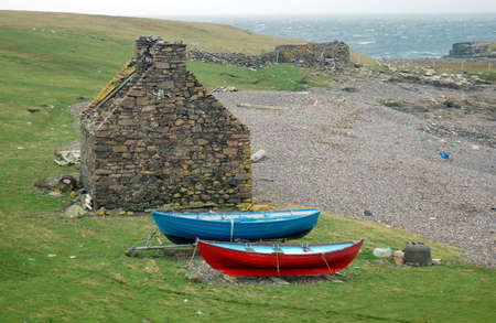 Abandoned house and Shetland boatsの写真素材