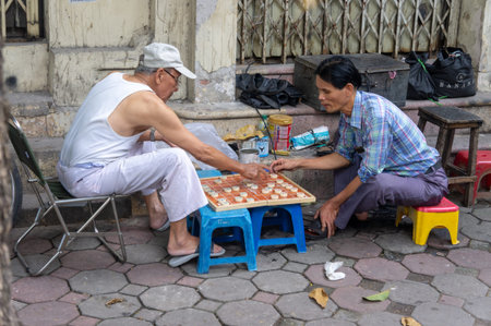 Hanoi, Vietnam - Oct 21, 2019. Street scene, two men play Chinese chess (xiangqi)