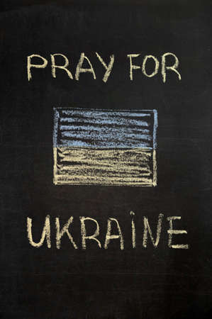 inscription Pray for Ukraine on a black board with chalk. ukraine flag drawn with chalk. verticalの写真素材