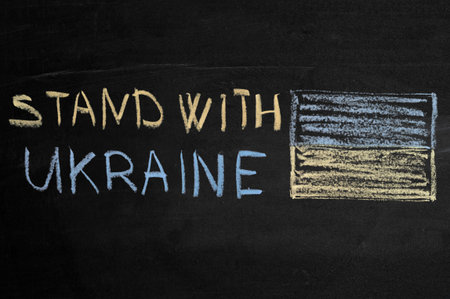 inscription stand with Ukraine on a black board with chalk. the flag of Ukraine is drawn on the left