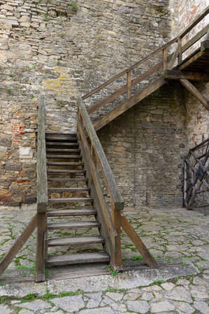 wooden staircase on the street against the background of a stone wall. outdoor wooden staircase in the castleの写真素材