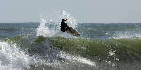 Guy doing an aerial on a nice little waveの写真素材
