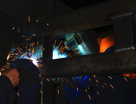 Two metal workers Mig welding some steel sections.