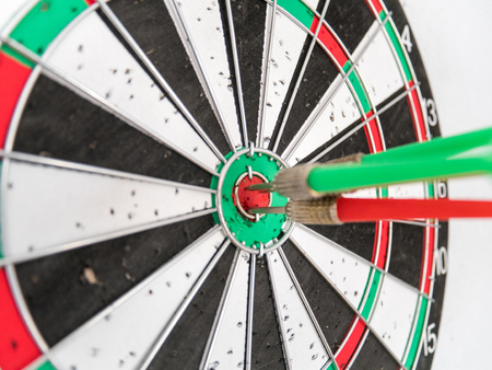 Close Up of Dart Holes on the Dart Board Due to Throwing Darts Multiple Times. Four Darts Hit the Red Bullseyeの写真素材