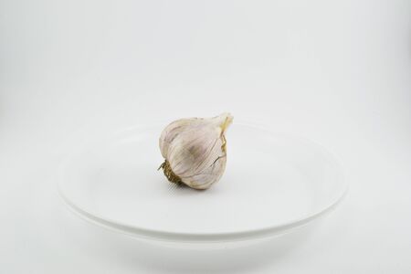 Garlic is lying on a plate on a white backgroundの写真素材