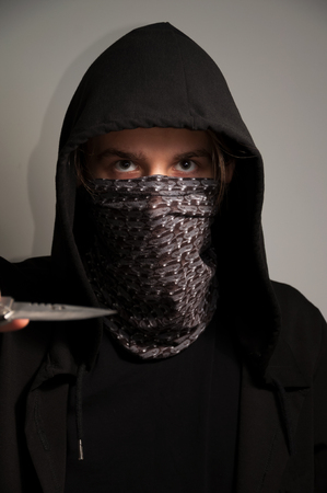 Portrait of hooded/masked man threatening with knife.の写真素材