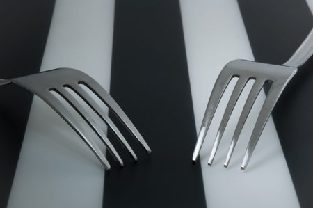 Two forks cross on striped background. 2 forks laying next to each other.