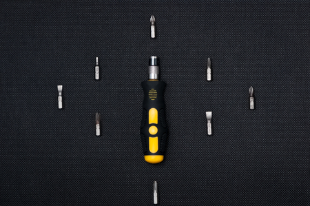 Black and yellow interchangable screwdriver with different bits surrounding. On dark dark background.の写真素材