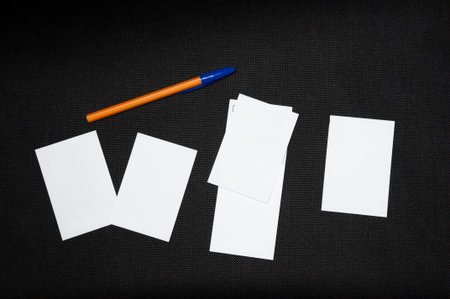 A blank sheets of paper next to a pen on a dark background. Layout for design. Top view, place for text.の写真素材