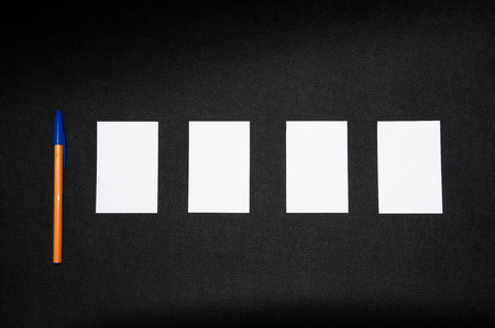 A blank sheets of paper next to a pen on a dark background. Layout for design. Top view, place for text.の写真素材