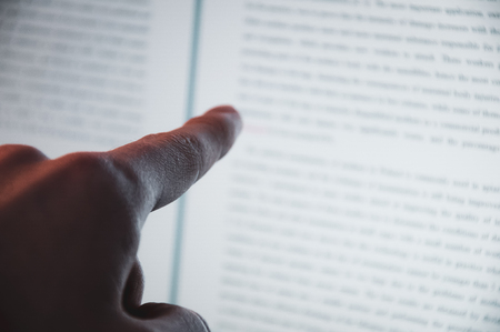 Closeup of finger touching screen on laptop-pc with shallow depth of field. Finger pointing on a specific sentence in a text document on laptop.の写真素材
