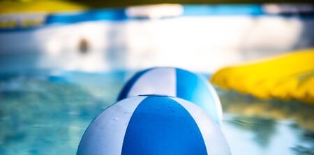 Inflatable colorful balls floating in the house garden swimming pool, with inflatable yellow mattress in the background. Strong sun light.の写真素材
