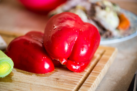 Half cut paprika on the wooden cutting board with pore on the side. Chicken meat in the background. Cooking ingredientsの写真素材