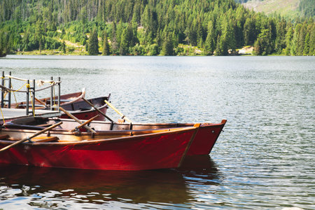 Several wooden red boats moored at the docks on small lake with forest in the backgroundの写真素材