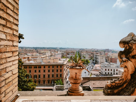 A breathtaking panoramic view of Rome captured from a historic balcony, showing iconic architecture and richly textured brickwork under a clear blue sky.の写真素材