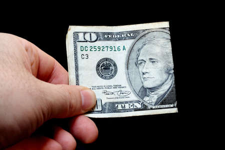 Man holding a ten dollar bill, isolated on black backgroundの写真素材