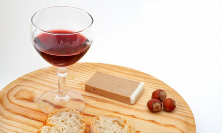 Pate, bread, glass of red wine, hazelnuts a wood plate on white backgroundの写真素材