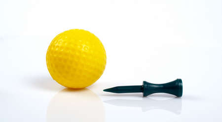 Yellow golfball and green tee with reflecting on white backgroundの写真素材