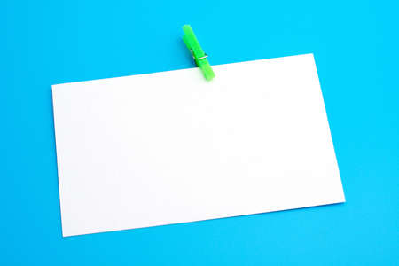 Isolated white paper with green clamp on blue backgroundの写真素材