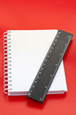 White notebook and measure, on red backgroundの写真素材