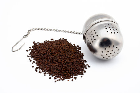 Tea and stainless steel tea ball on white background