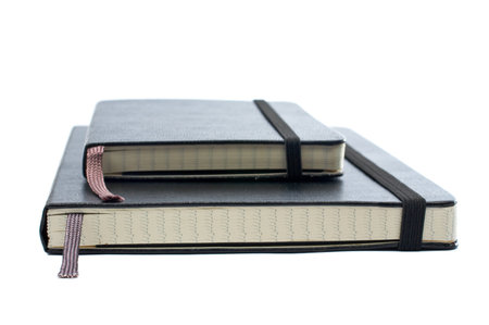 Two blacks notebooks with soft shadow on white background. Small DOF