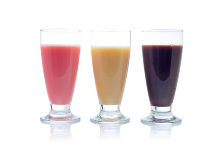 A three milkshakes with flavors of strawberry, vanilla and chocolate reflected on white backgroundの写真素材