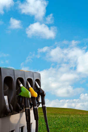 Three gas pump nozzles over a nature background