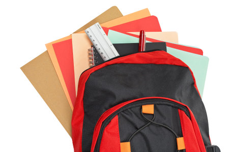 A black and red backpack with school material over a white backgroundの写真素材