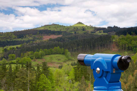 Coin telescope on focus over mountain landscape with cloudy sky blurredの写真素材