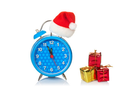 Blue alarm clock with christmas hat and gifts, reflected on white backgroundの写真素材