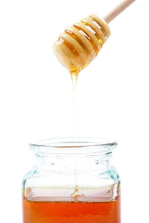 Pouring honey on glass jar, on white backgroundの写真素材