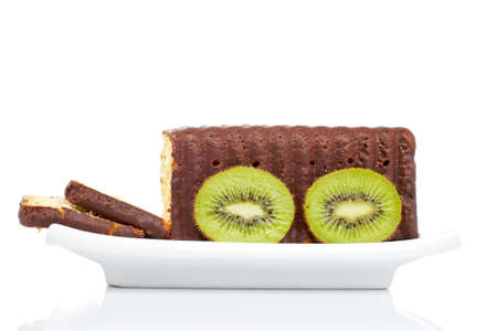 Slices of cake with kiwi on a dish, reflected over white background. Shallow DOFの写真素材