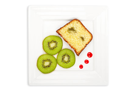 Slice of cake with kiwi on a white plate with soft shadow on white background. Shallow DOFの写真素材