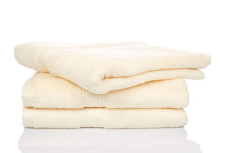 A yellow towels stacked reflected on white backgroundの写真素材