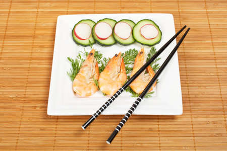 Prawns on the white plate and chopsticks on bamboo mat. Shallow depth of fieldの写真素材