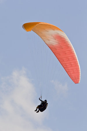 A man with a colorful paraglider flying in the sky