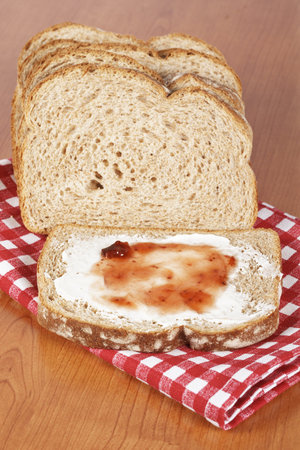Toast with butter and strawberry jam glass jar on square mat background. Shallow depth of field