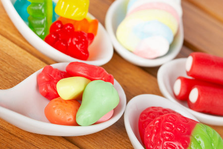 Assortment of candies in the spoons with soft shadow in the wooden background. Shallow depth of...