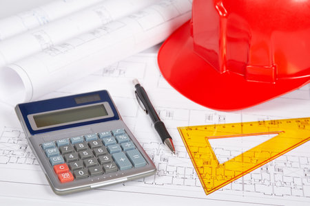 Construction plans with hard hat and drawing tools. Shallow depth of field