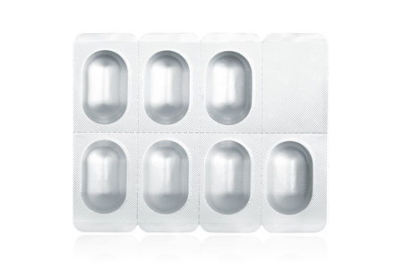 Blister pack containing medical pills reflected on white background