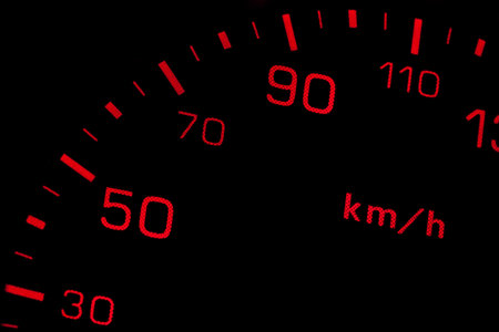 Orange neon speedometer over a black background. Shallow depth of field