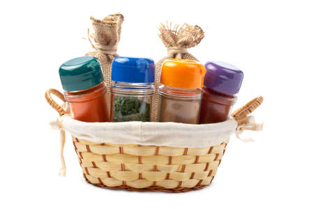 Assortment of spices jars for prepare tasty food in a basket over a white backgroundの写真素材