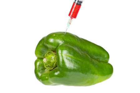 A green pepper injected with a syringe containing blue fluid, isolated on white background. Shallow depth of fieldの写真素材