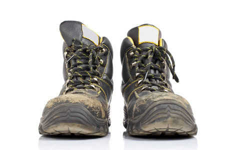 A pair of old work boots with soft shadow on white background