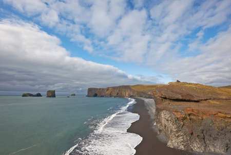 Black sand beach with Lundadrangur Rock Arch in Dyrholaey, South Coast, Icelandの写真素材